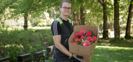 Hautausmaalla työntekijä Samuli Apell sylissään laatikollinen kukkia.
