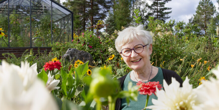 Leena Kumpusalo hymyilee kukkapellon keskellä.